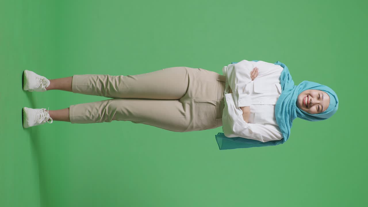 녹색 스크린 배경 스튜디오에 서 있는 동안 미소 짓고 팔을 는 아시아 무슬림 여성의 몸이 가득 차 있습니다.