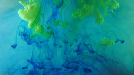spreading of blue, green paint in a liquid space.