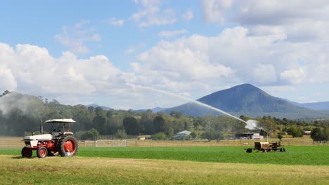 tractor irrigating field with mountain backdrop