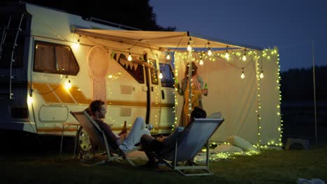 group of young friends spending time on the camping and drinking beer in the evening.