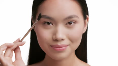 young asian woman applying eyebrow makeup