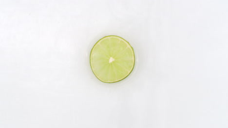 On-a-white-background-cut-into-slices-of-lime-sprinkled-with-water-spray.-Juicy-fresh-lime-in-slow-motion.