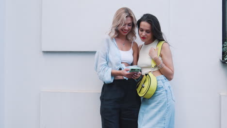 dos mujeres jóvenes mirando su teléfono