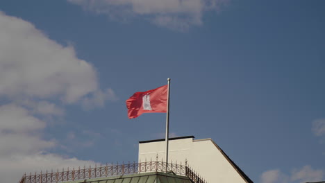 flag of hamburg city waving in the wind with blue sky and clouds in the back on top of building