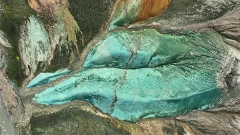 aerial drone azimuthal view at medium altitude, spanning from grænihryggur rock to the valley, in landmannalaugar, iceland, emphasizing the medium tones of orange and green