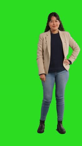 Vertical-Video-Full-Length-Studio-Portrait-Of-Female-Teacher-Or-Businesswoman-Standing-Against-Green-Screen-With-Hand-On-Hip