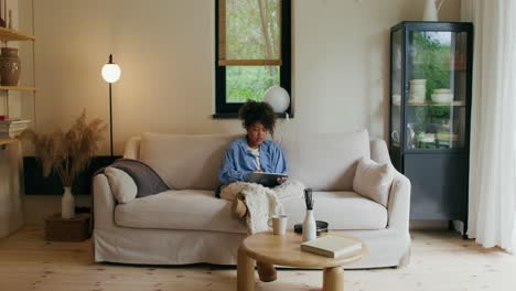 woman using tablet on couch in living room