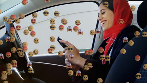 animación de emojis que caen sobre una mujer con hijab usando un teléfono inteligente