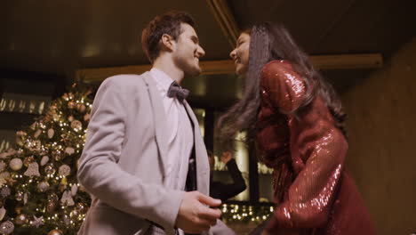 bottom view of couple dressed in elegant clothes dance with friends at the new year's party