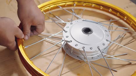technician man working motorcycle wheel has spokes weave up on mechanic new steel wheel