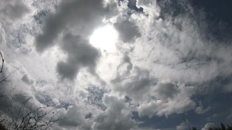 time lapse of cloudscape with bright sun shining and revealing itself behind clouds.