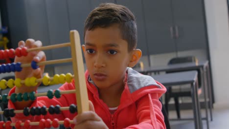 front view of asian schoolboy solving math problem with abacus at desk in a classroom at school 4k
