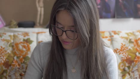 Hispanic-woman-in-black-glasses-gazes-down,-holds-ball-of-yarn