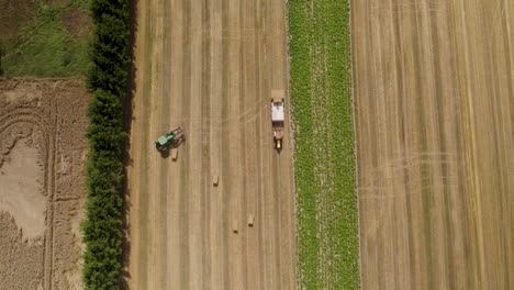 Farmers-working-on-the-field,-driving-tractors-with-hay-bale-load