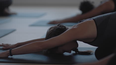 Gesunde-Kaukasische-Yoga-Frau-Praktiziert-Kinderpose-Meditation-Mit-Einer-Gruppe-Gemischtrassiger-Frauen,-Die-Den-Fitness-Lebensstil-Genießen-Und-Bei-Sonnenaufgang-Flexiblen-Körper-Auf-Einer-Trainingsmatte-Im-Trainingsstudio-Trainieren