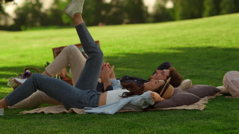 dreamy girl and guy looking at sky in park. couple holding hands on picnic