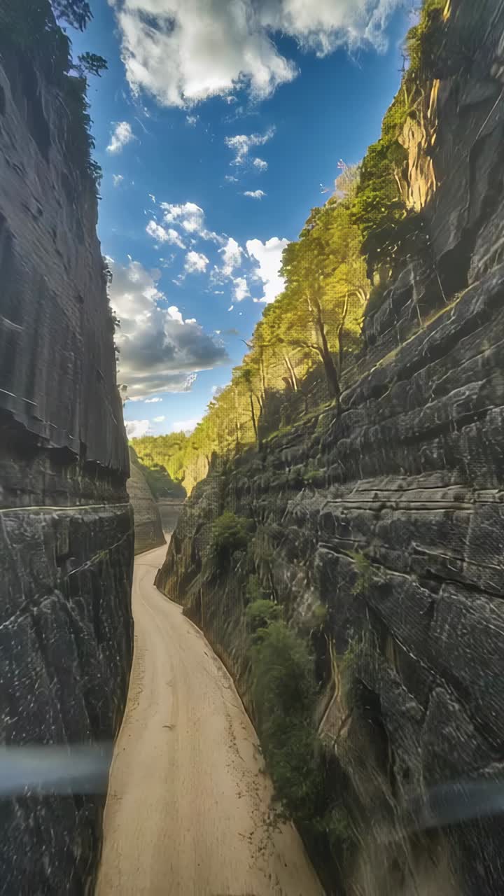 Vertikales Video: Die Kamera bewegt sich vorwärts in eine Schlucht und enthüllt einen sandigen Pfad und geschichtete Klippen