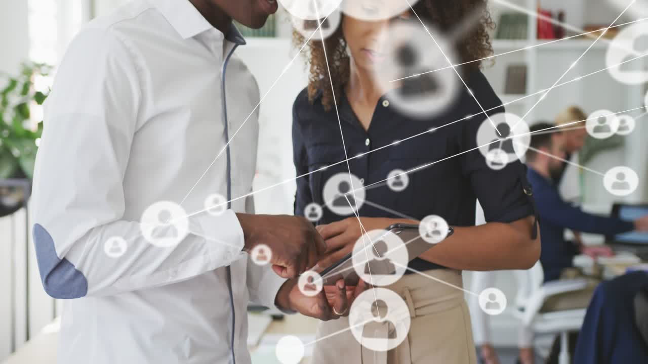 Woman holding tablet while man tapping initiating network icons linking across business for review