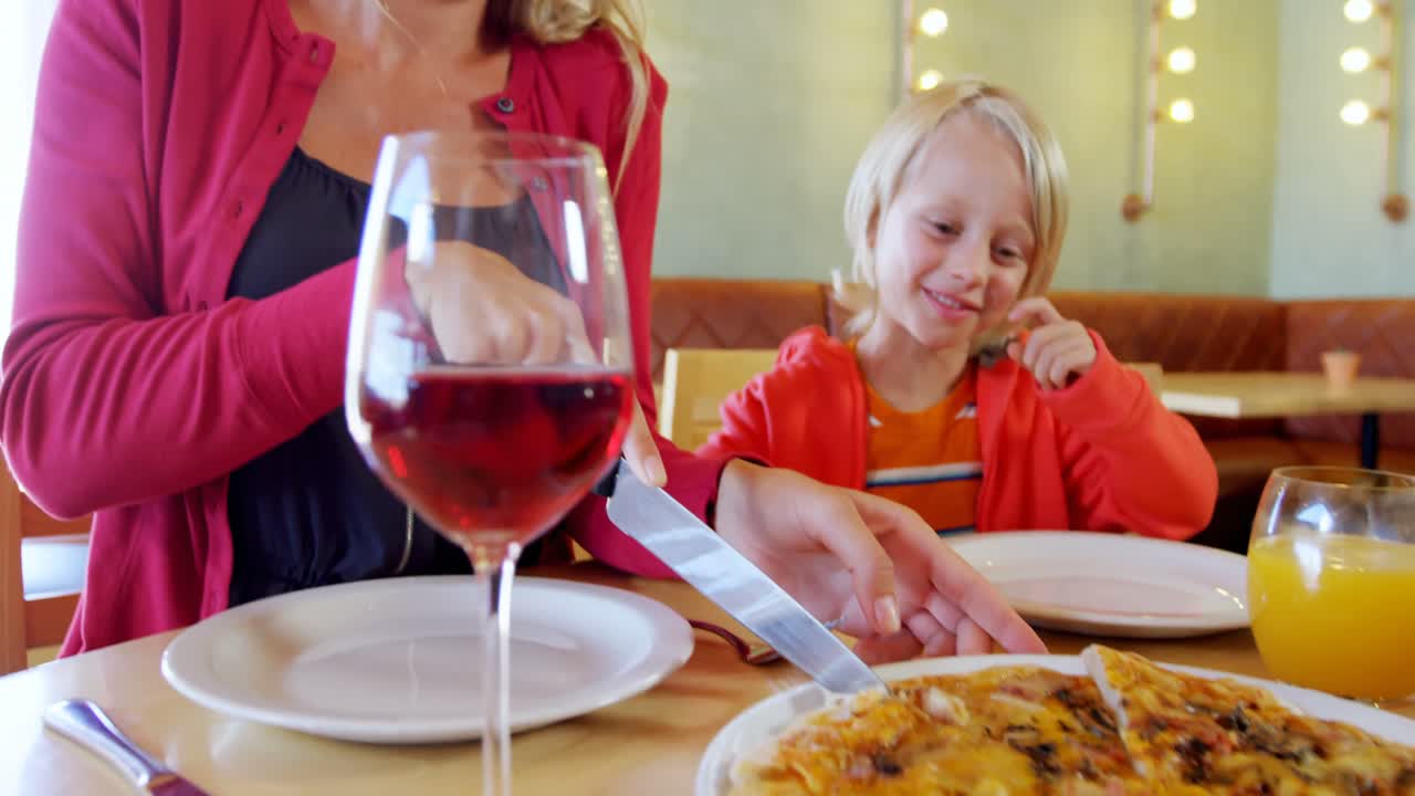 madre e hijo comiendo pizza en el restaurante 4k