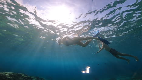 slow motion shot of a young caucasian woman diving in crystal clear blue waters with a man