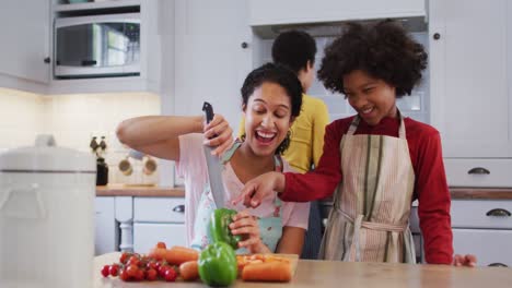 Mixed-race-lesbian-couple-and-daughter-preparing-food-in-kitchen