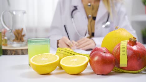 Mujer-Dietista-Trabajando-En-Una-Mesa-Llena-De-Fruta.