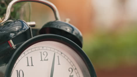 close-up-black-old-clock-classic-style-showing-minutes-past-three-on-blurry-background-tilt-down