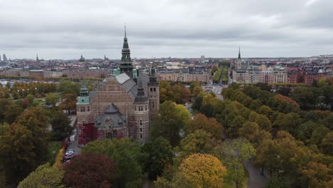 Vista-Aérea-De-Arriba-Hacia-Abajo-Del-Museo-Nórdico-En-Estocolmo,-Suecia,-Se-Puede-Ver-La-Isla-Djurgarden,-Al-Fondo-La-Ciudad-Con-Sus-Canales-Y-Barcos