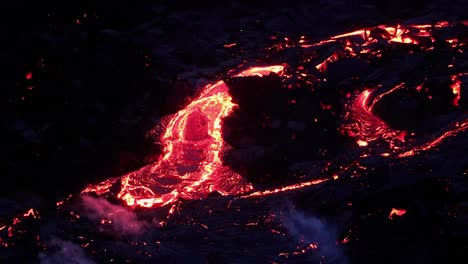 river of hot lava flowing from crater of fagradalsfjall volcano during eruption at night