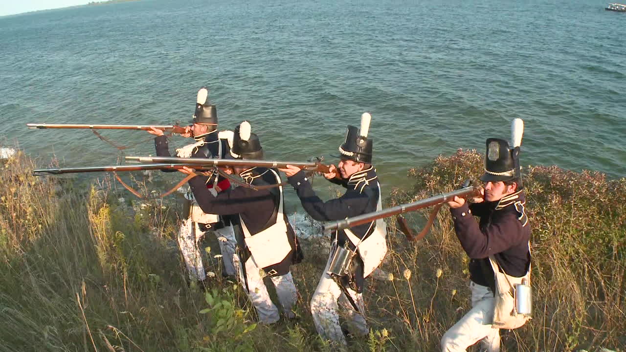 1812년 전쟁의 텔레비전 스타일 재연에서 남자들은 도착한 병사들과 전투를 벌이기 위해 숲에서 나옵니다.