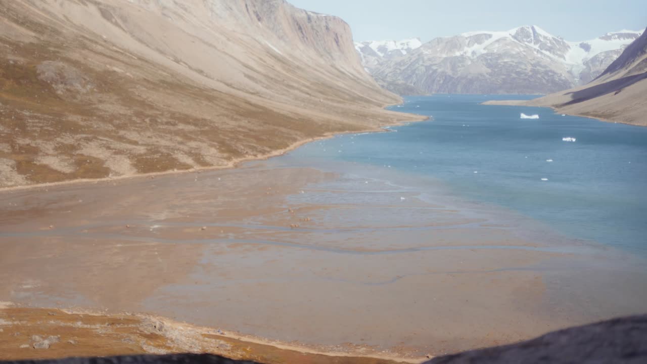 Timelapse of a sunny day in a Greenland fjord, capturing the rising water levels due to the ebb and flow of tides, showcasing the stunning natural beauty and dynamic movement of the sea.