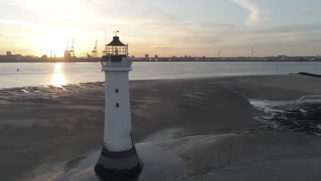 vista aérea a través del faro británico y las grúas de los astilleros costeros que brillan intensamente amanecer horizonte órbita izquierda a la ciudad costera