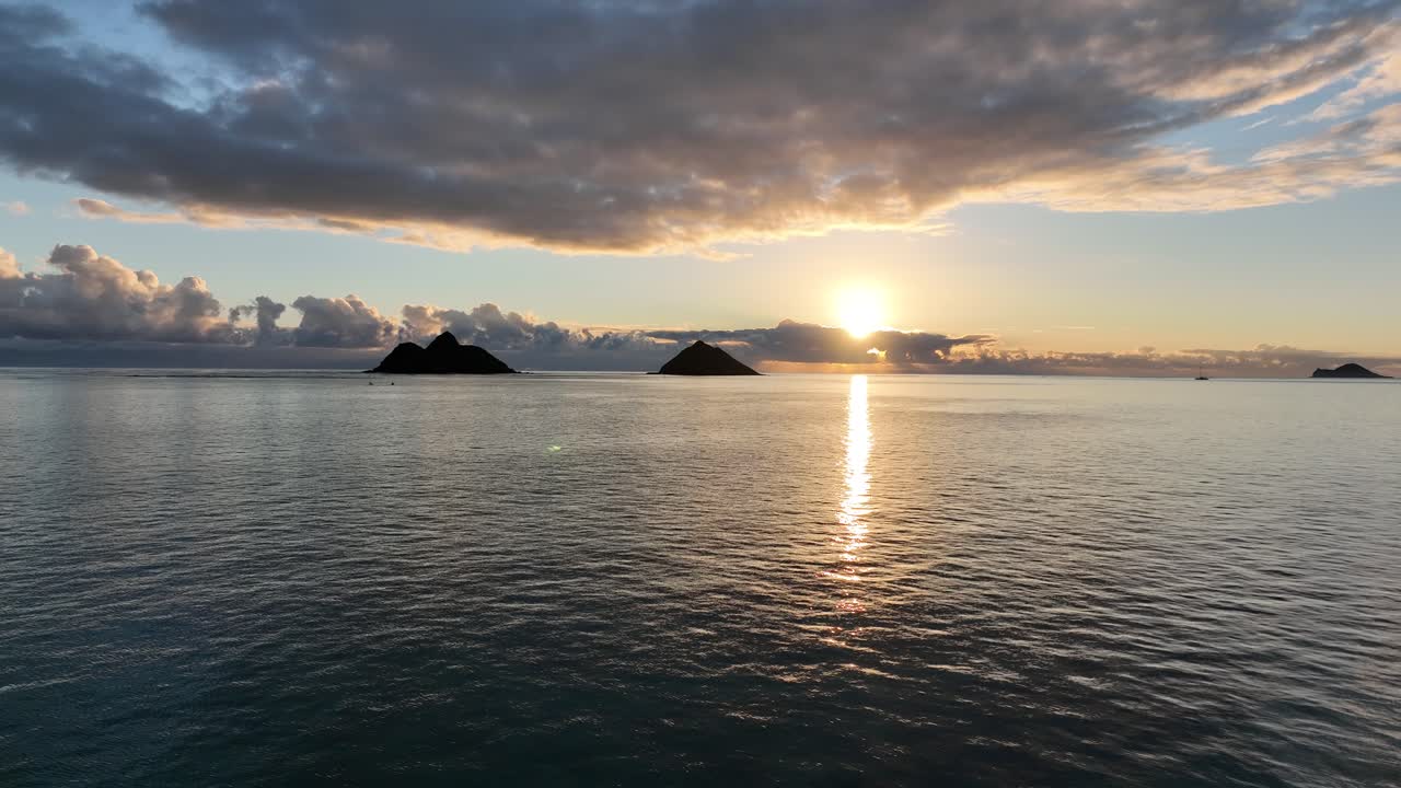 맑은 빈 물과 구름 사이로 떠오르는 태양이 있는 섬으로 이동하는 일출 모쿨루아 섬의 실루엣 드론 영상