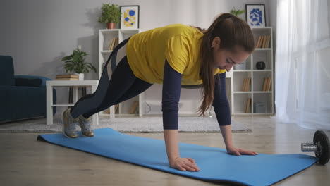 fitness en el hogar durante el aislamiento y el bloqueo mujer está entrenando en el piso de la sala de estar manteniéndose en forma cuidando de una buena condición física