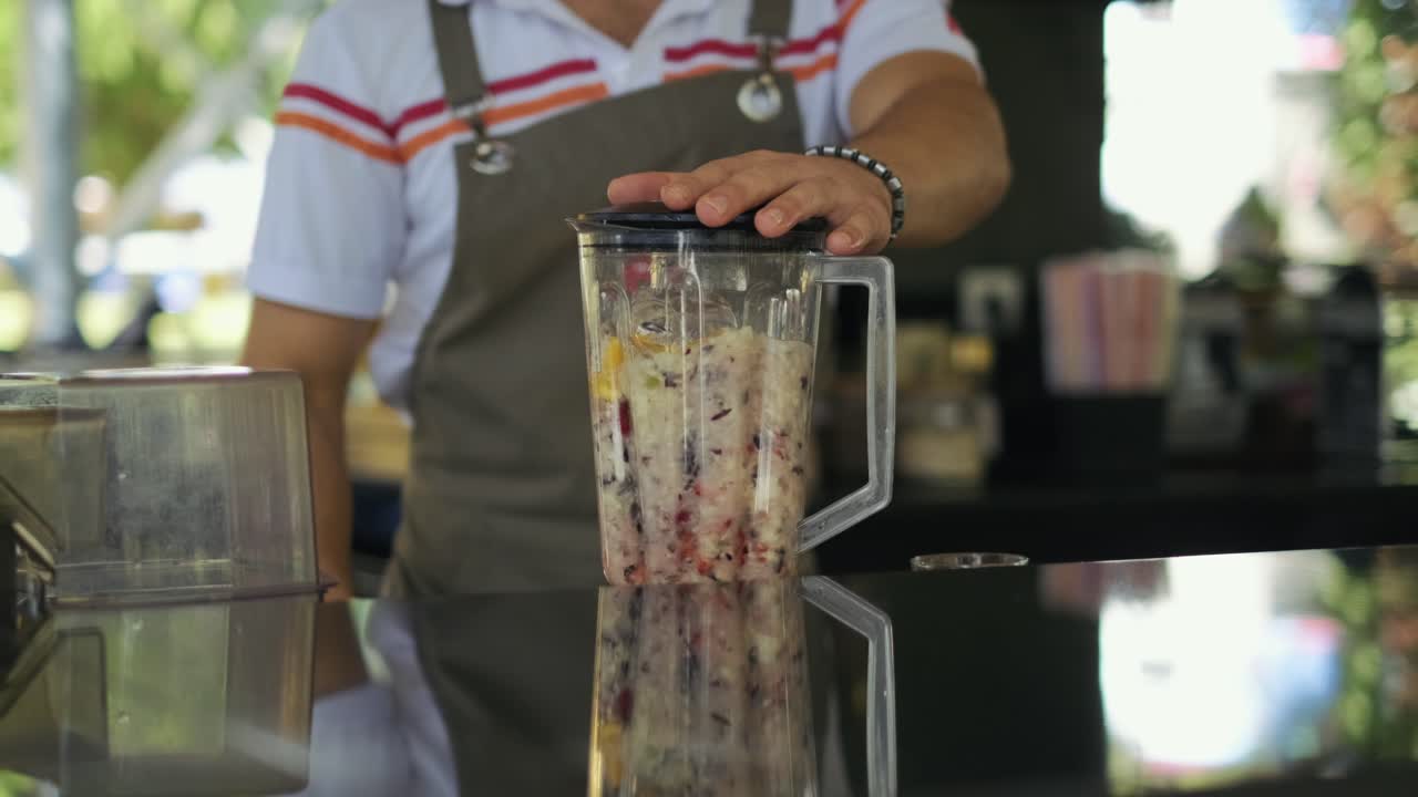 남자가 믹서기에 과일을 섞고 있다