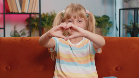 young child kid girl makes symbol of love showing heart sign to camera express romantic feelings