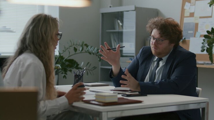 Businessman Having Conversation with Female Colleague at Office Desk