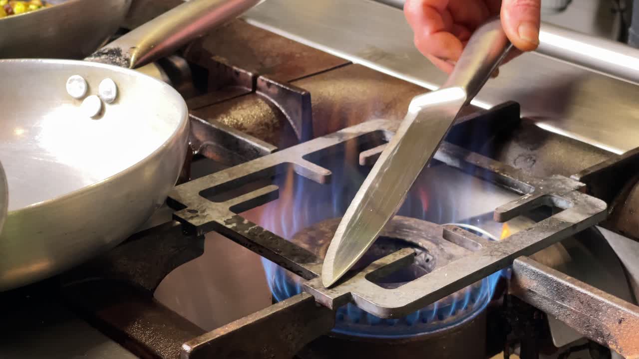 chef calentando cuchillo de cocina en un fuego de cocina profesional para cortar foie-gras