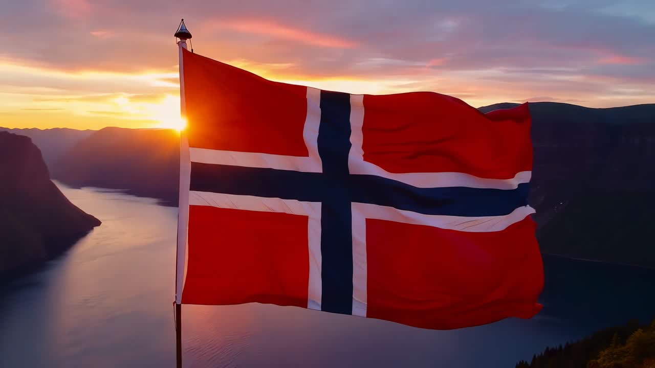 Vaiende norsk flagg som reagerer på kraftig vind ved fjordutsikten, fanger linseflare