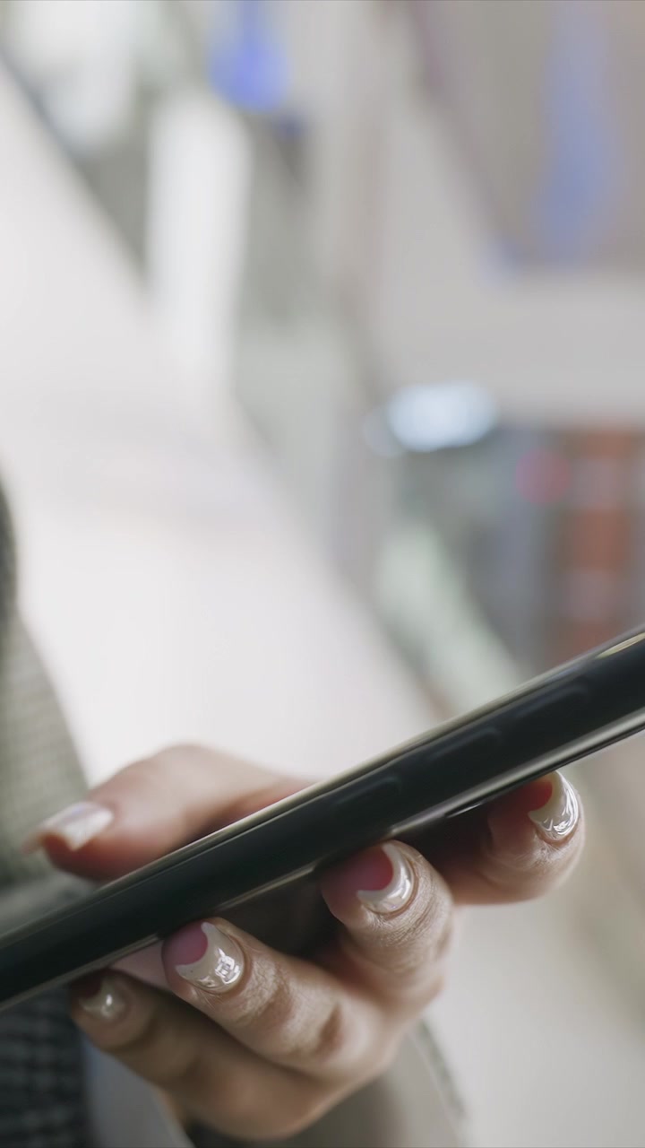 Close up of woman hand holding smartphone with manicured nails. Focus remains on fingers and device emphasizing nail design details. Soft indoor lighting creates natural highlights