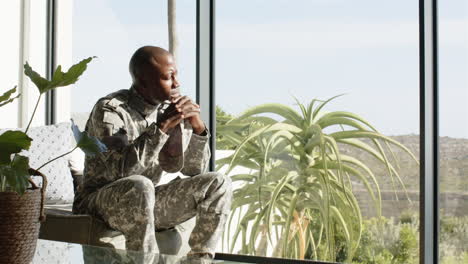 contemplating, man in military uniform sitting by window with thoughtful expression