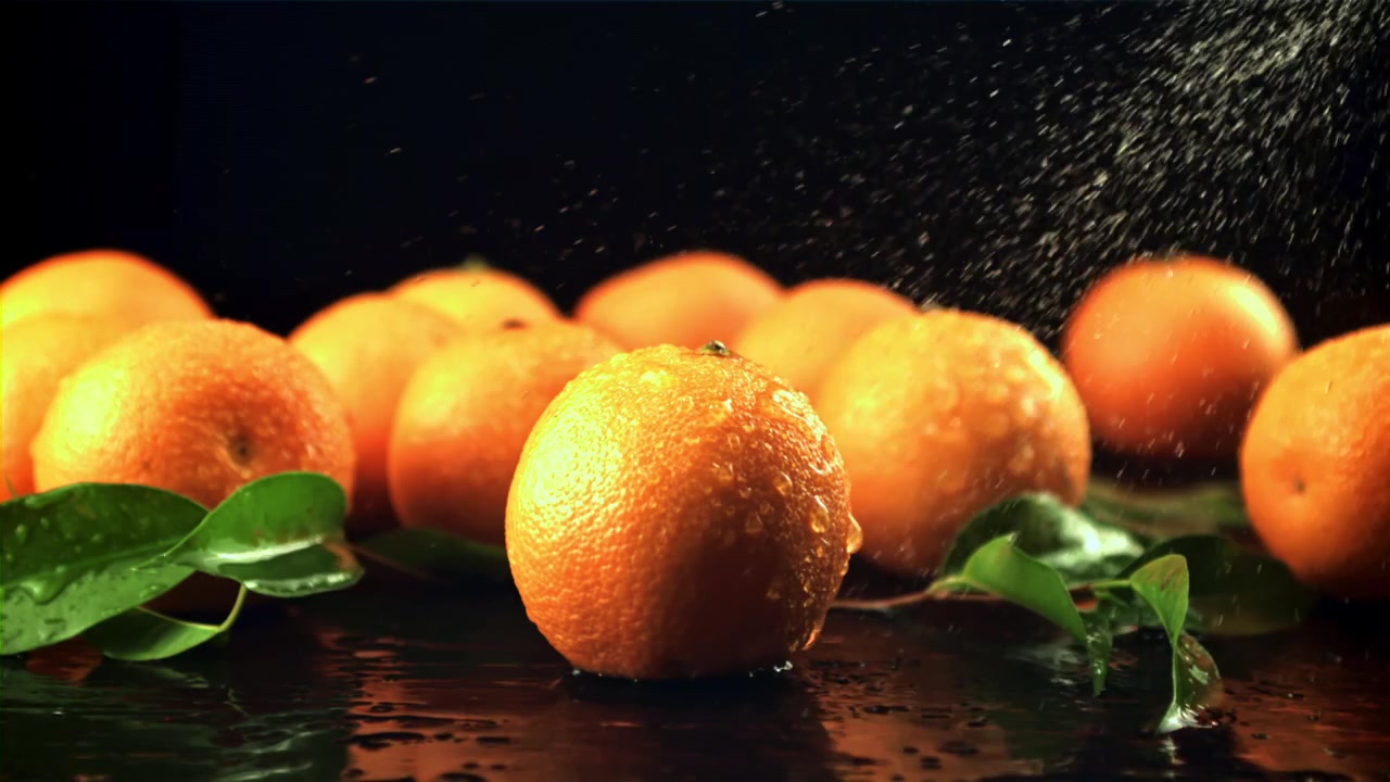 Arance fresche e foglie verdi cosparse d'acqua al rallentatore