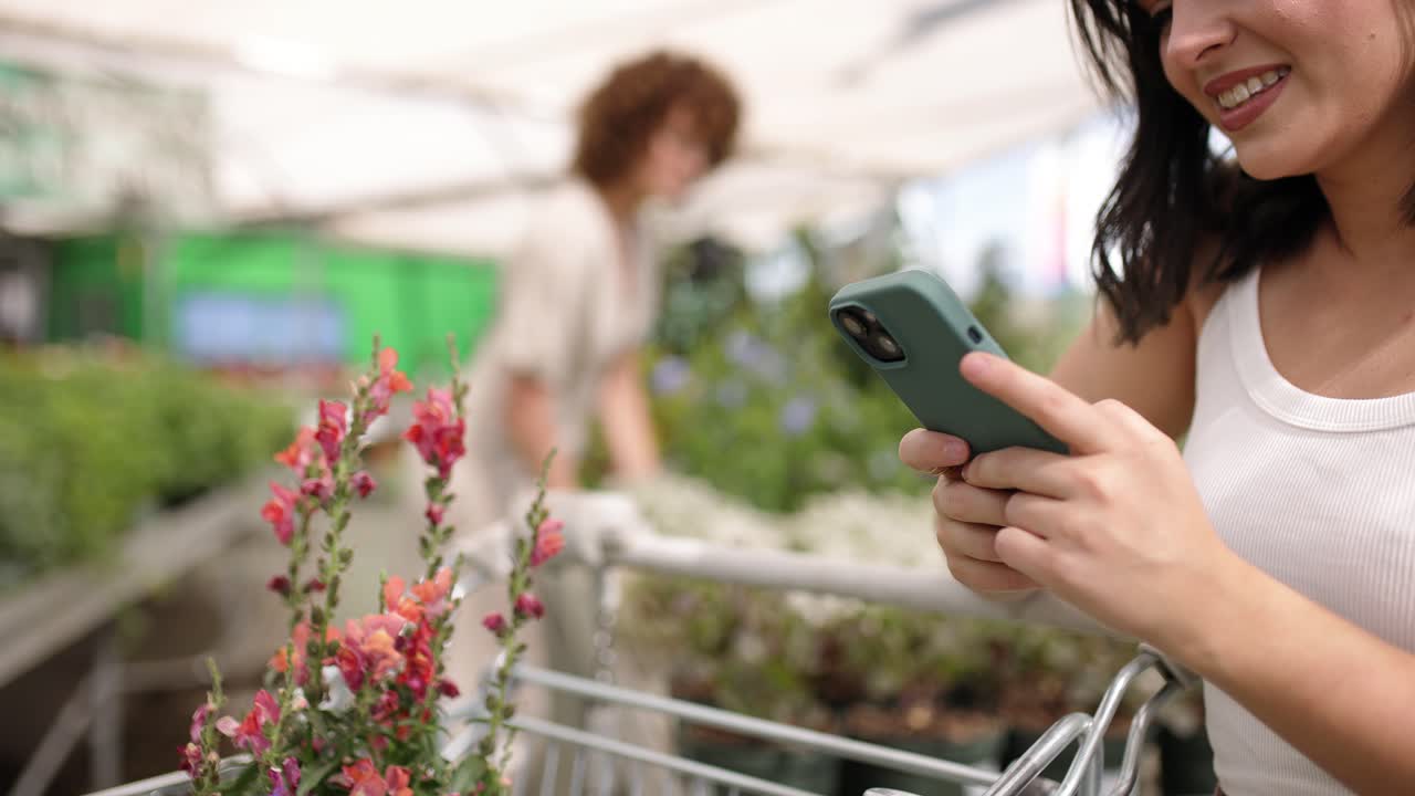 Happy female using mobile phone while shopping in nursery
