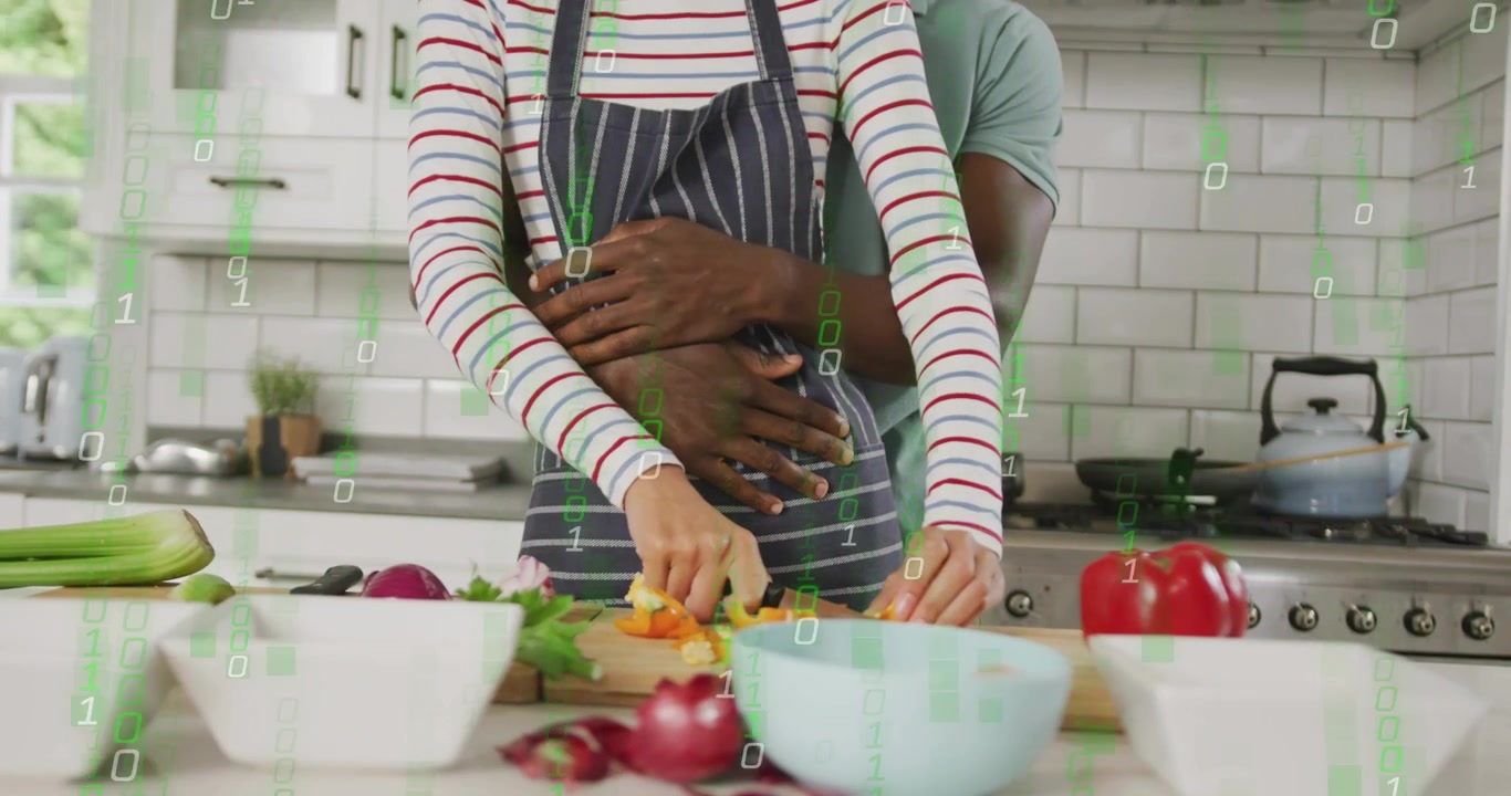 Woman holding knife starting carrot chopping in kitchen while man hugging with binary overlaying
