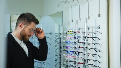 young man in optics store. man in optical center trying new eyeglasses