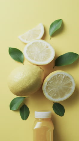 vertical video of sliced lemon and juice with copy space over yellow background