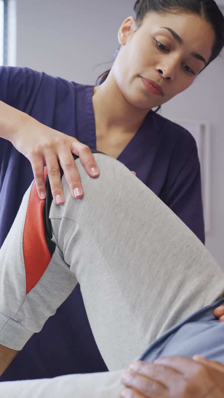 video vertical de una doctora asiática haciendo ejercicio con un paciente afroamericano en el hospital