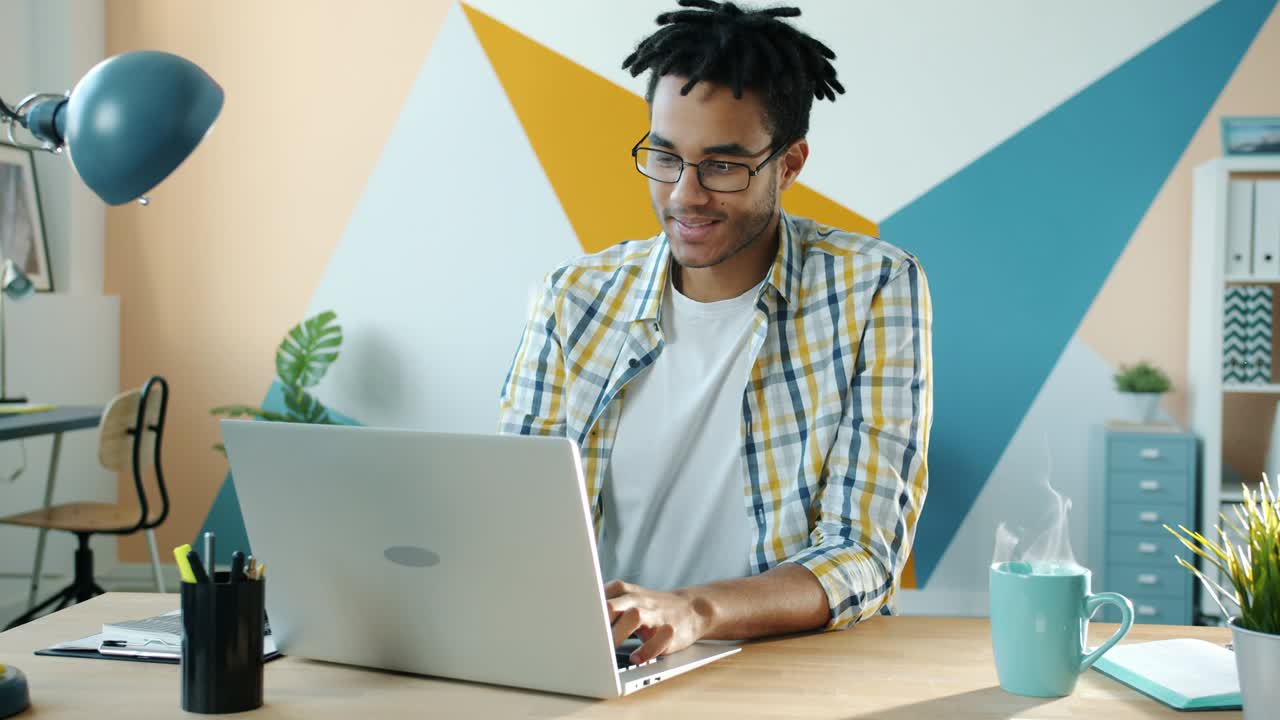 Cinemagraph of African American man employee working with laptop and smiling