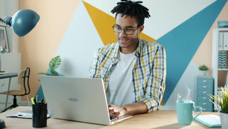 cinemagraph of african american man employee working with laptop and smiling