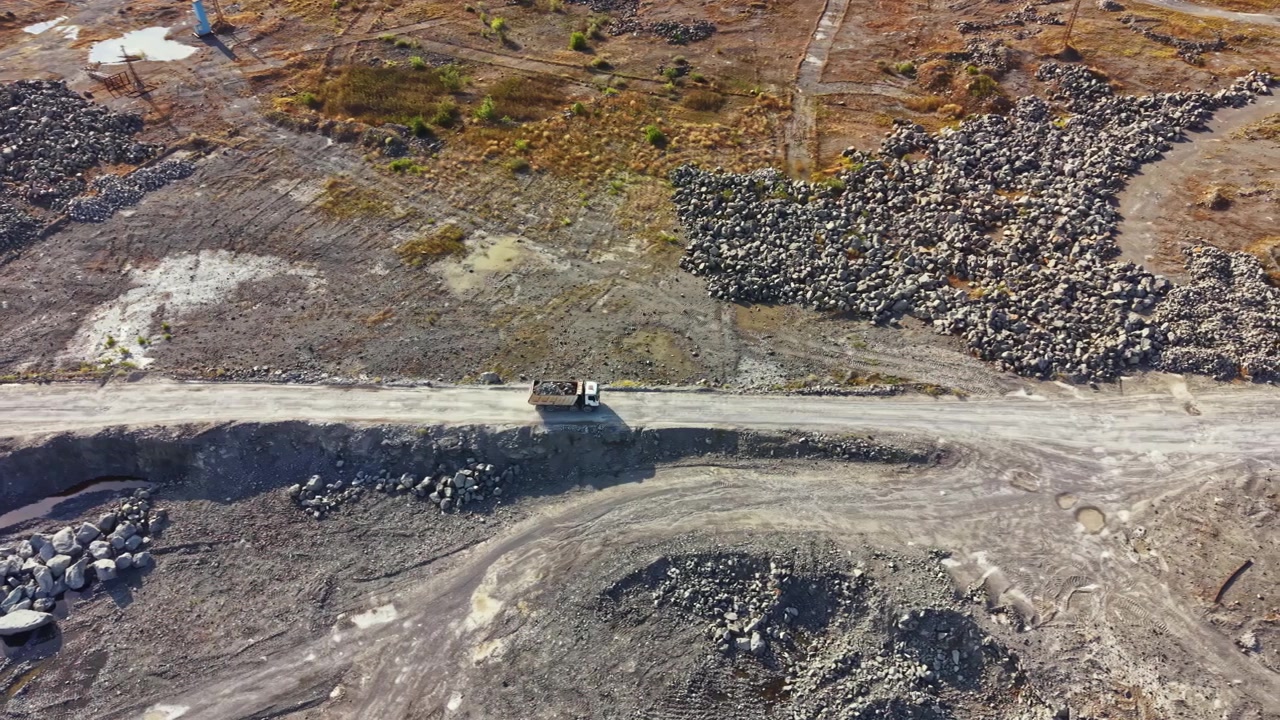 Granite quarry showing work area with machinery and extracted stone near water and rocks in surrounding landscape